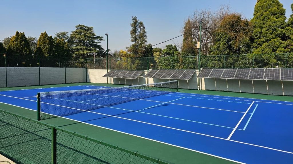 Blue tennis court with green perimeter fencing and net