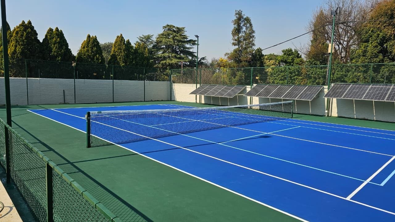 Blue tennis court with net and floodlights by Kiki Projects