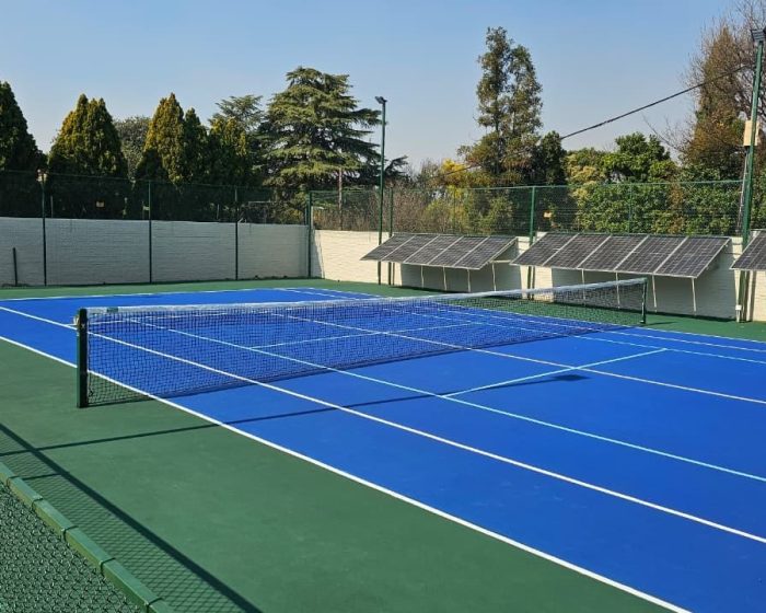 Blue tennis court with net and floodlights by Kiki Projects
